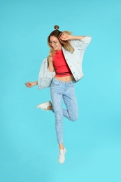 Full length portrait of emotional woman jumping on color background