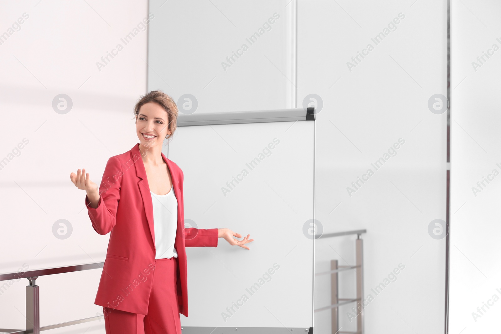 Photo of Female business trainer giving presentation on whiteboard indoors