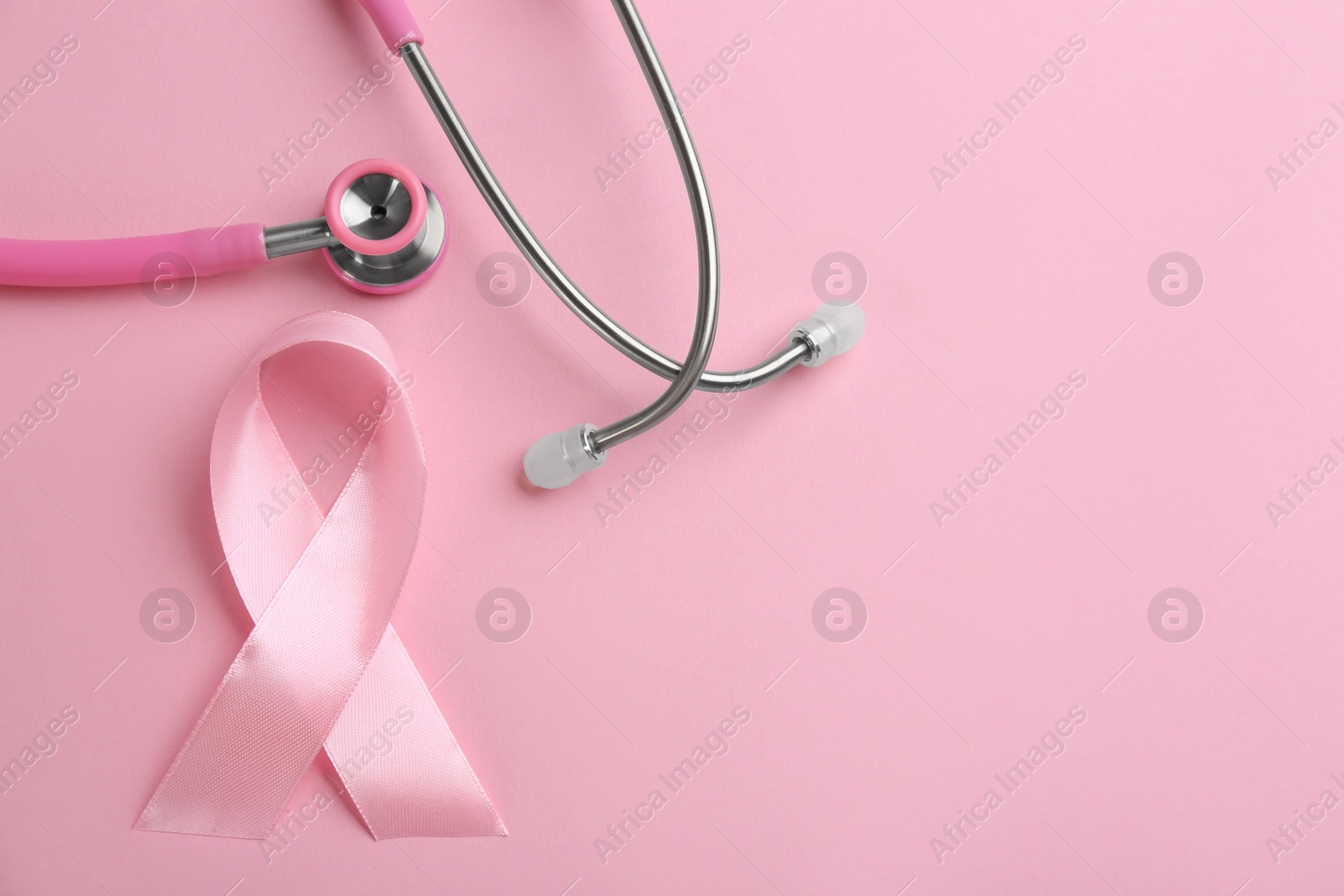 Photo of Pink ribbon and stethoscope on color background, flat lay with space for text. Breast cancer concept