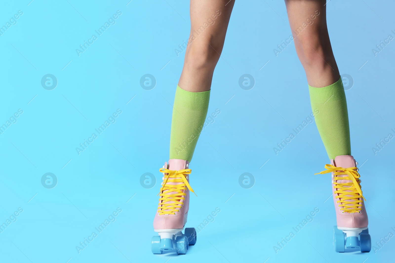 Photo of Woman with vintage roller skates on color background, closeup. Space for text