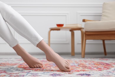 Woman on carpet with pattern at home, closeup. Space for text