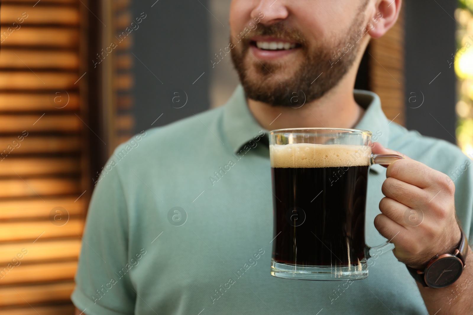 Photo of Young man with cold kvass outdoors, closeup. Traditional Russian summer drink