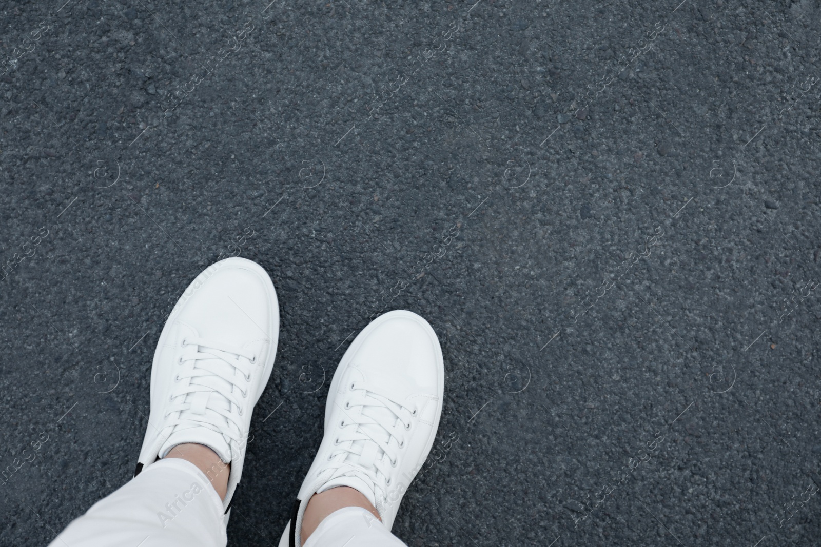 Photo of Woman standing on asphalt, top view. Space for text