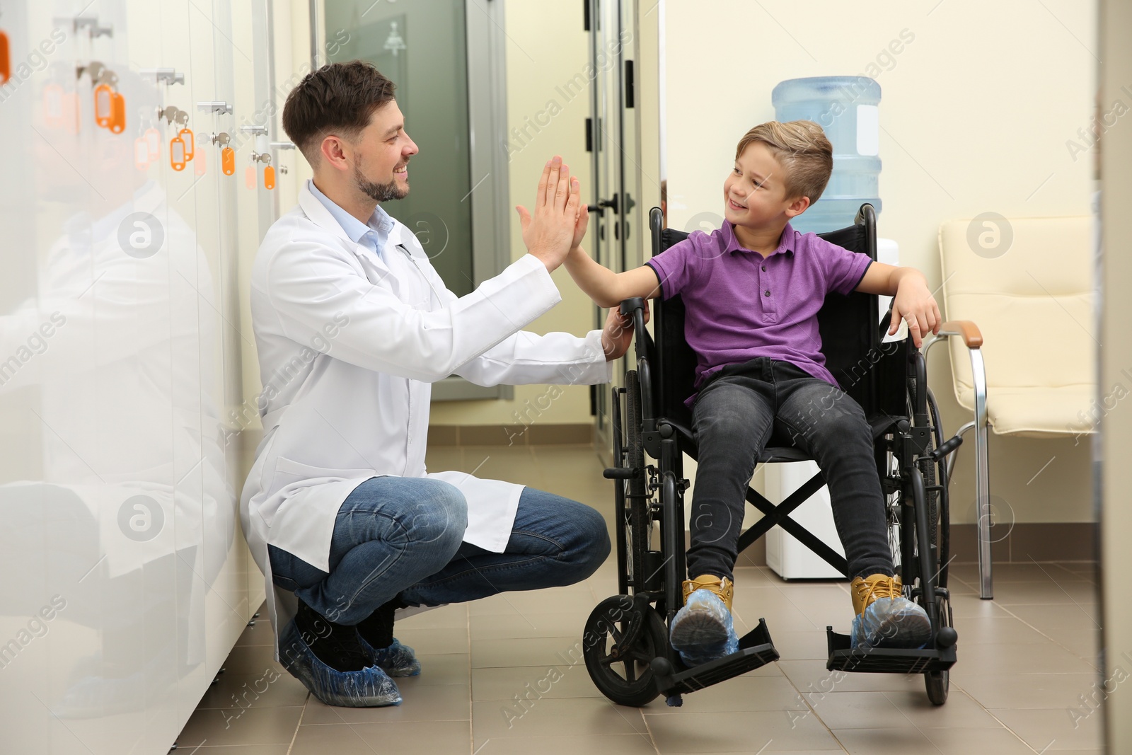 Photo of Doctor and little child in wheelchair at hospital