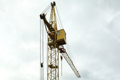 Construction site with tower crane under beautiful cloudy sky, low angle view