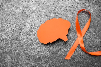 Photo of Orange ribbon and paper brain cutout on grey table, flat lay with space for text. Multiple sclerosis awareness