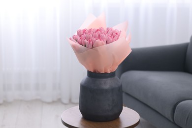 Photo of Bouquet of beautiful pink tulips in vase on wooden table indoors
