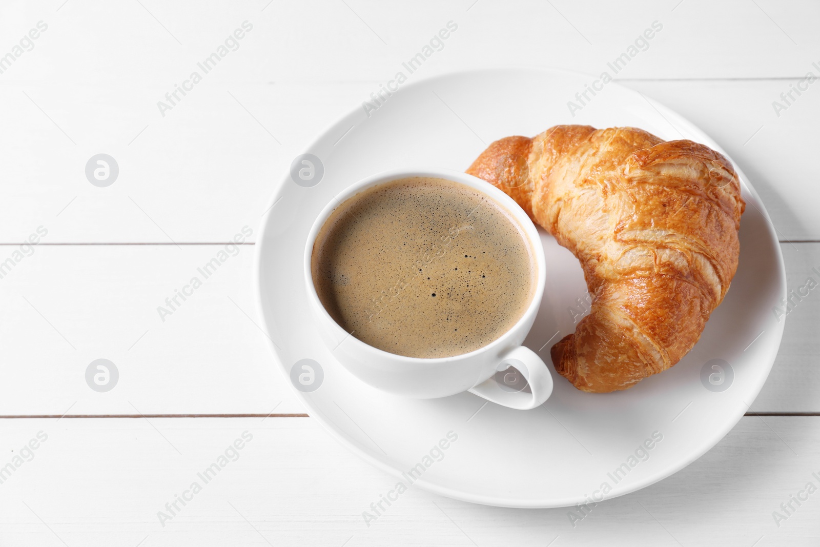 Photo of Breakfast time. Fresh croissant and coffee on white wooden table. Space for text