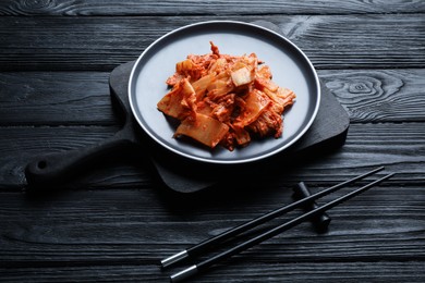 Photo of Delicious kimchi with Chinese cabbage served on black wooden table