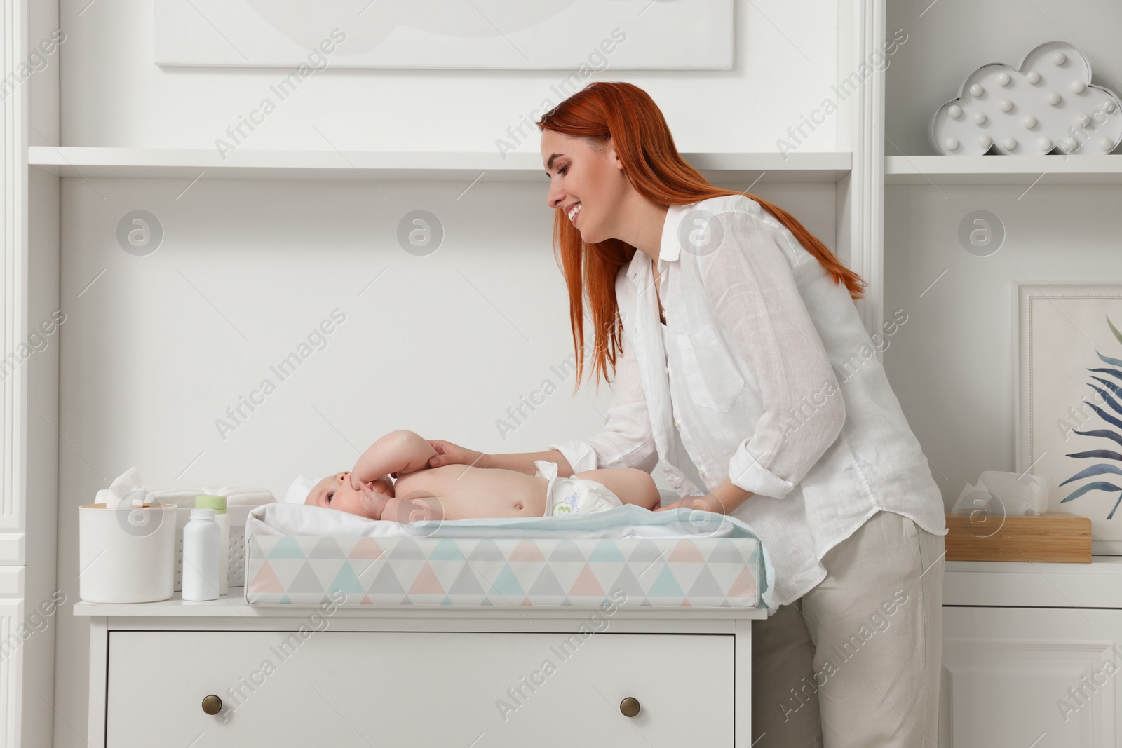 Photo of Mother changing her baby's diaper on table at home