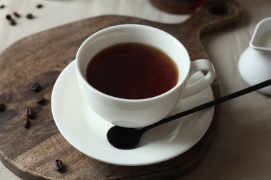 Photo of Tasty tea in cup and coffee beans on light table