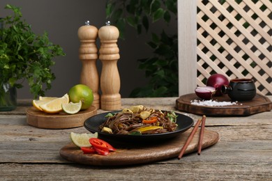 Photo of Stir-fry. Tasty noodles with meat and vegetables served on wooden table