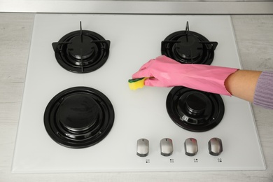 Woman cleaning gas stove with sponge, closeup