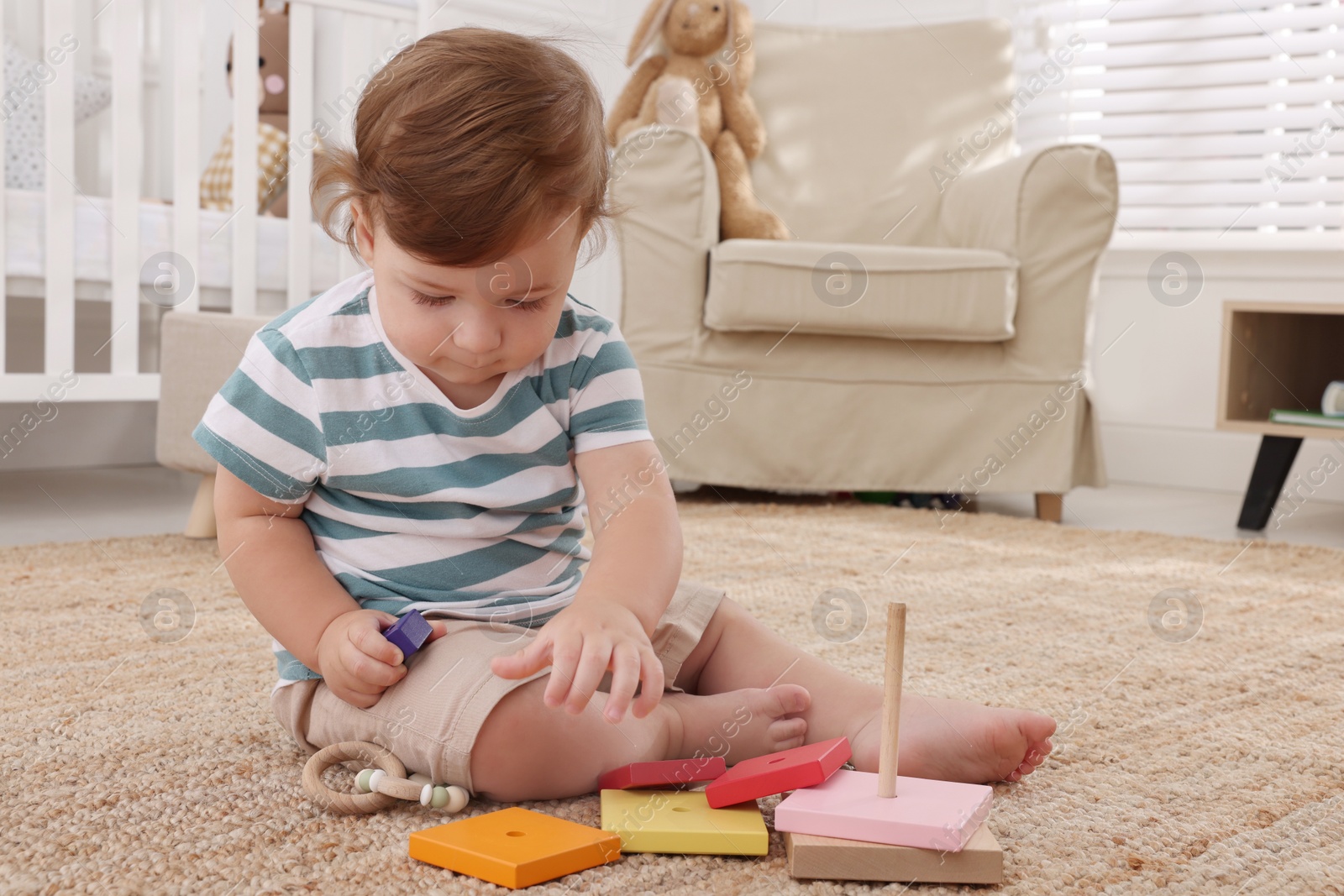 Photo of Cute little boy playing with toys on floor indoors