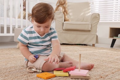 Photo of Cute little boy playing with toys on floor indoors