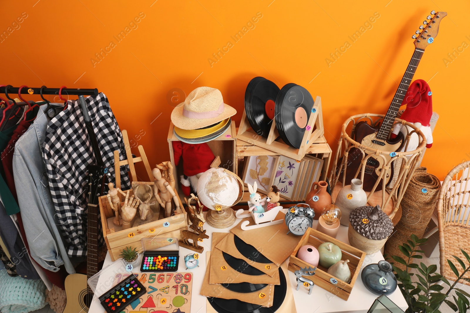 Photo of Many different stuff near orange wall. Garage sale