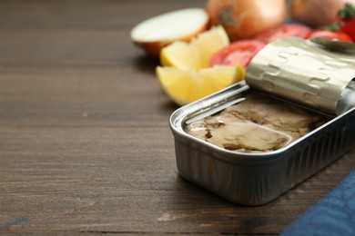 Open tin can of tasty cod liver on wooden table, closeup. Space for text