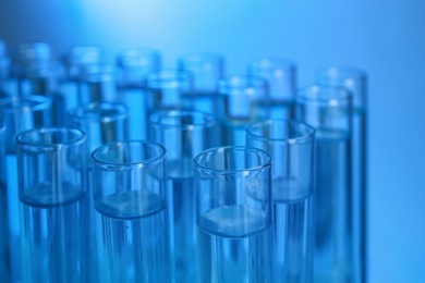 Photo of Test tubes with liquid against color background, closeup. Laboratory analysis