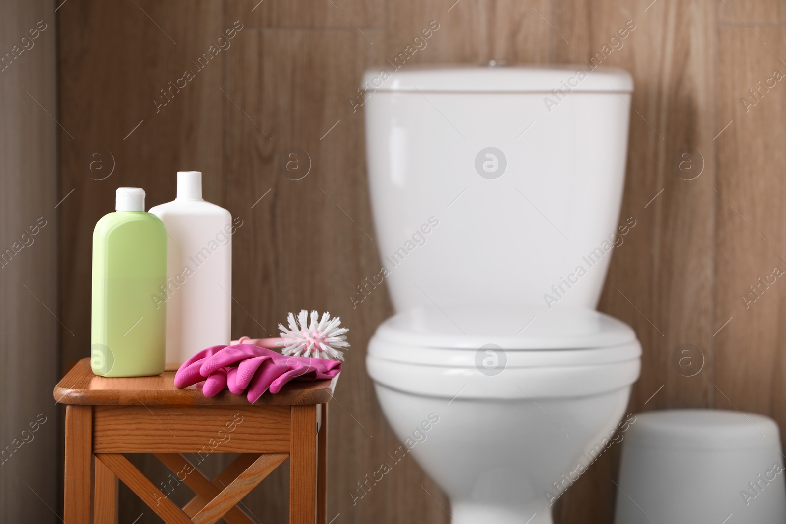 Photo of Cleaning supplies on stool near toilet bowl indoors, space for text