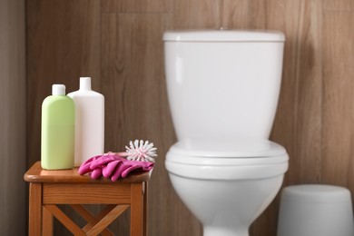 Photo of Cleaning supplies on stool near toilet bowl indoors, space for text