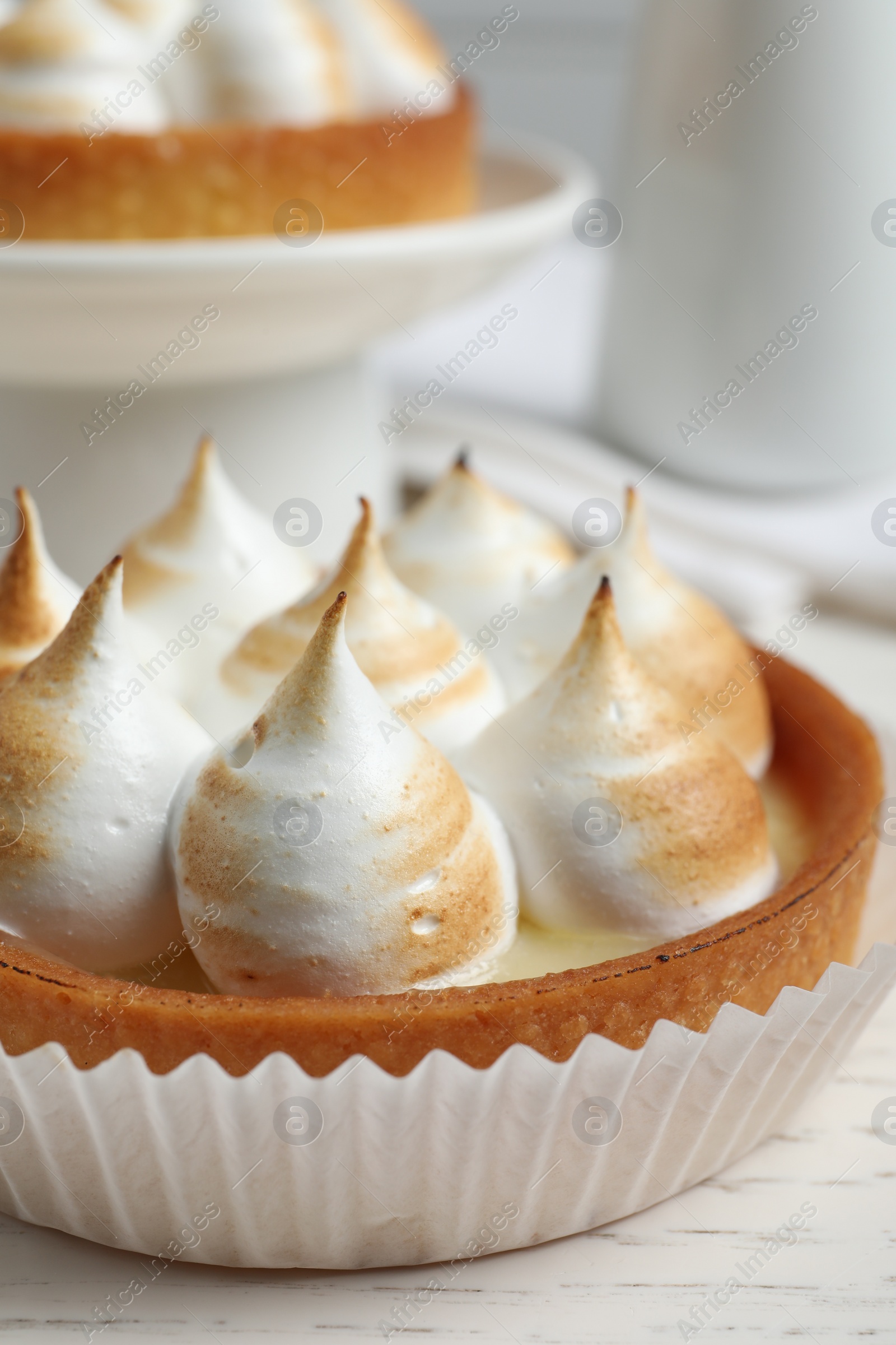 Photo of Tartlet with meringue on white table, closeup. Delicious dessert