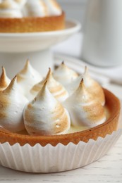 Photo of Tartlet with meringue on white table, closeup. Delicious dessert