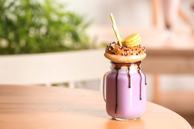 Mason jar with delicious milk shake on table against blurred background. Space for text