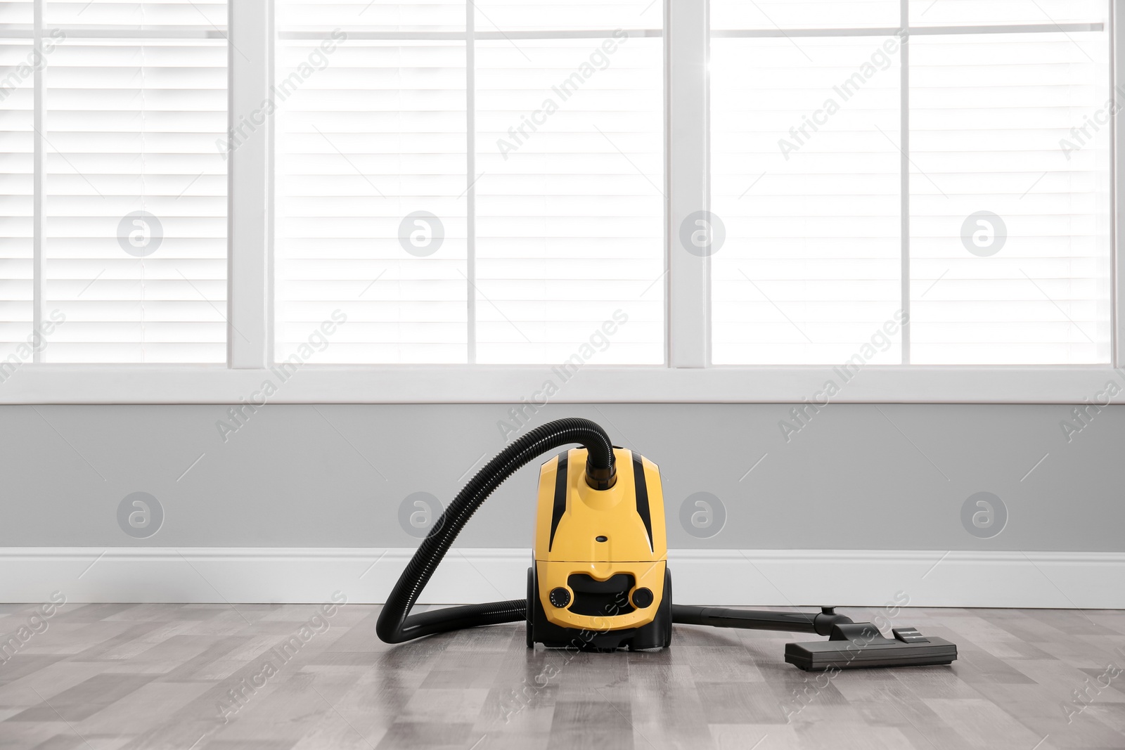 Photo of Modern yellow vacuum cleaner on floor indoors