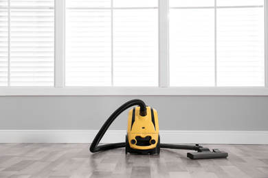 Modern yellow vacuum cleaner on floor indoors