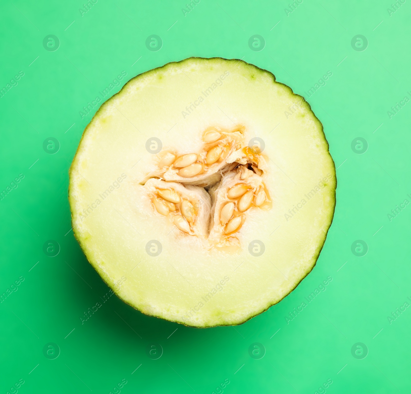 Photo of Half of ripe tasty melon on green background, top view