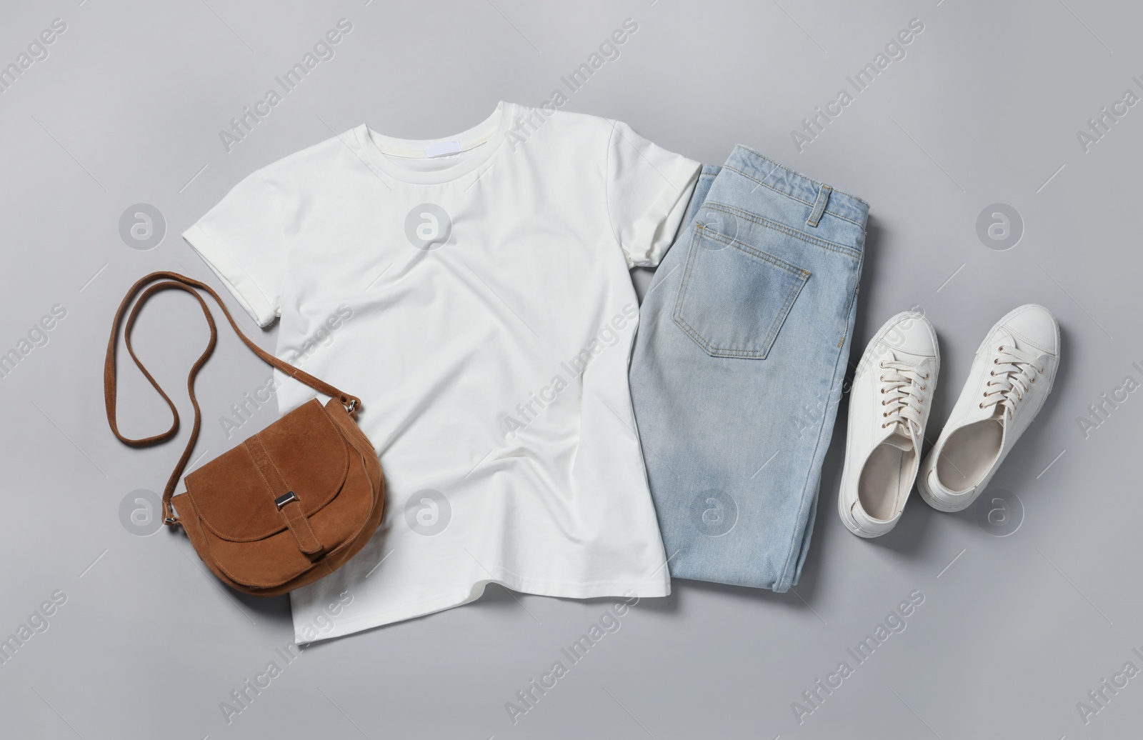 Photo of Stylish t-shirt, jeans and sneakers on light grey background, flat lay