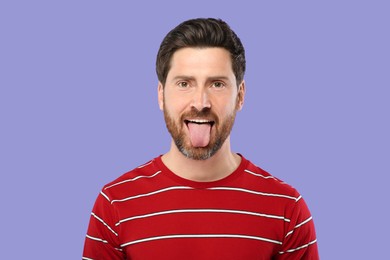Photo of Man showing his tongue on violet background
