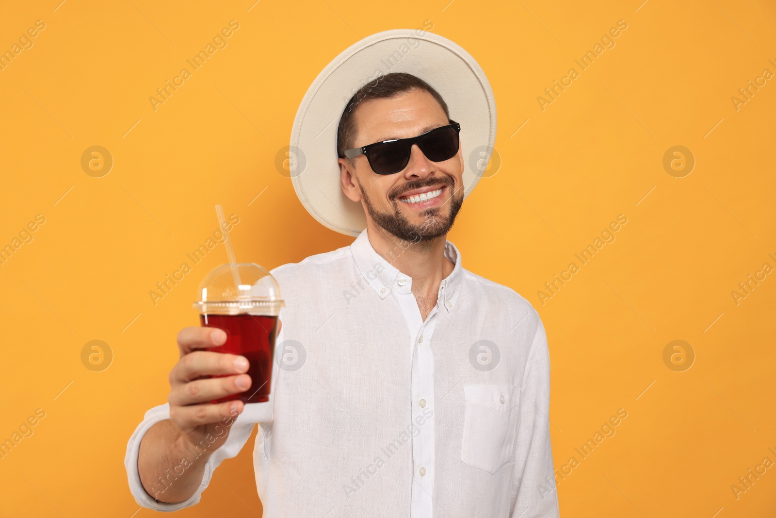 Photo of Man holding plastic cup of delicious juice on orange background