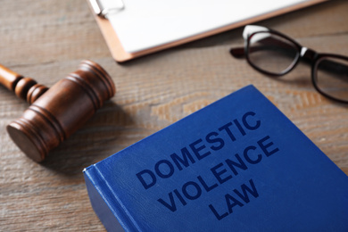 Photo of Domestic violence law and gavel on wooden table, closeup
