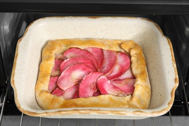 Photo of Delicious galette with apples in oven, closeup