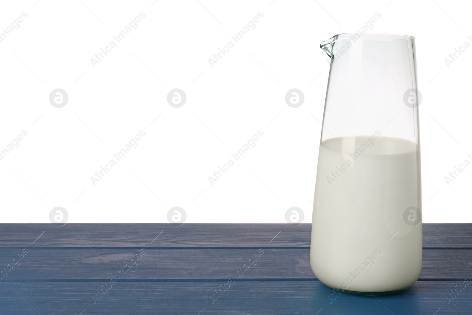 Photo of One jug of tasty milk on blue wooden table against white background