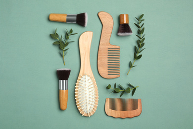 Photo of Flat lay composition with modern hair combs and brush on green background
