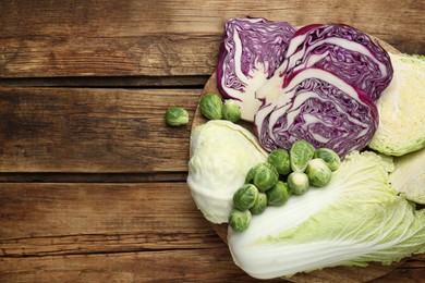 Photo of Different types of cabbage on wooden table, flat lay. Space for text