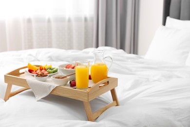 Photo of Tray with tasty breakfast on bed at home, space for text