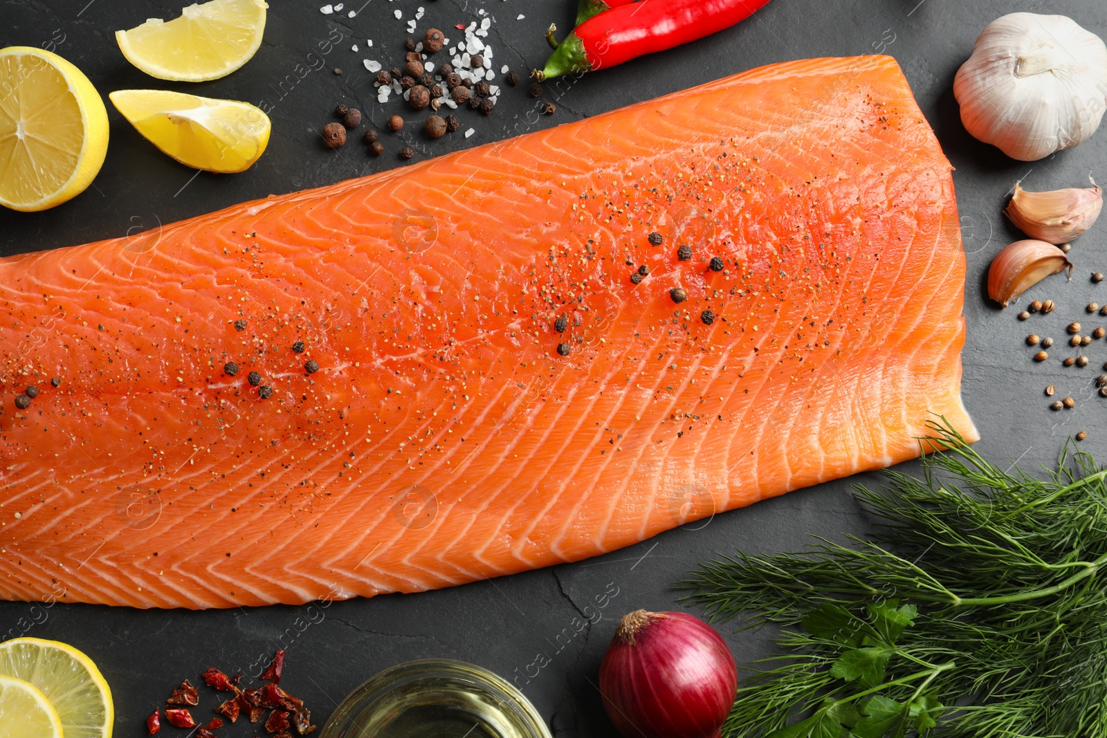 Photo of Fresh raw salmon and ingredients for marinade on black table, flat lay