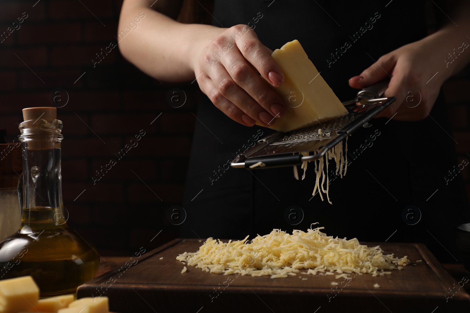 Photo of Woman grating cheese at wooden table, closeup