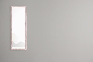 Photo of Large mirror hanging on empty grey wall