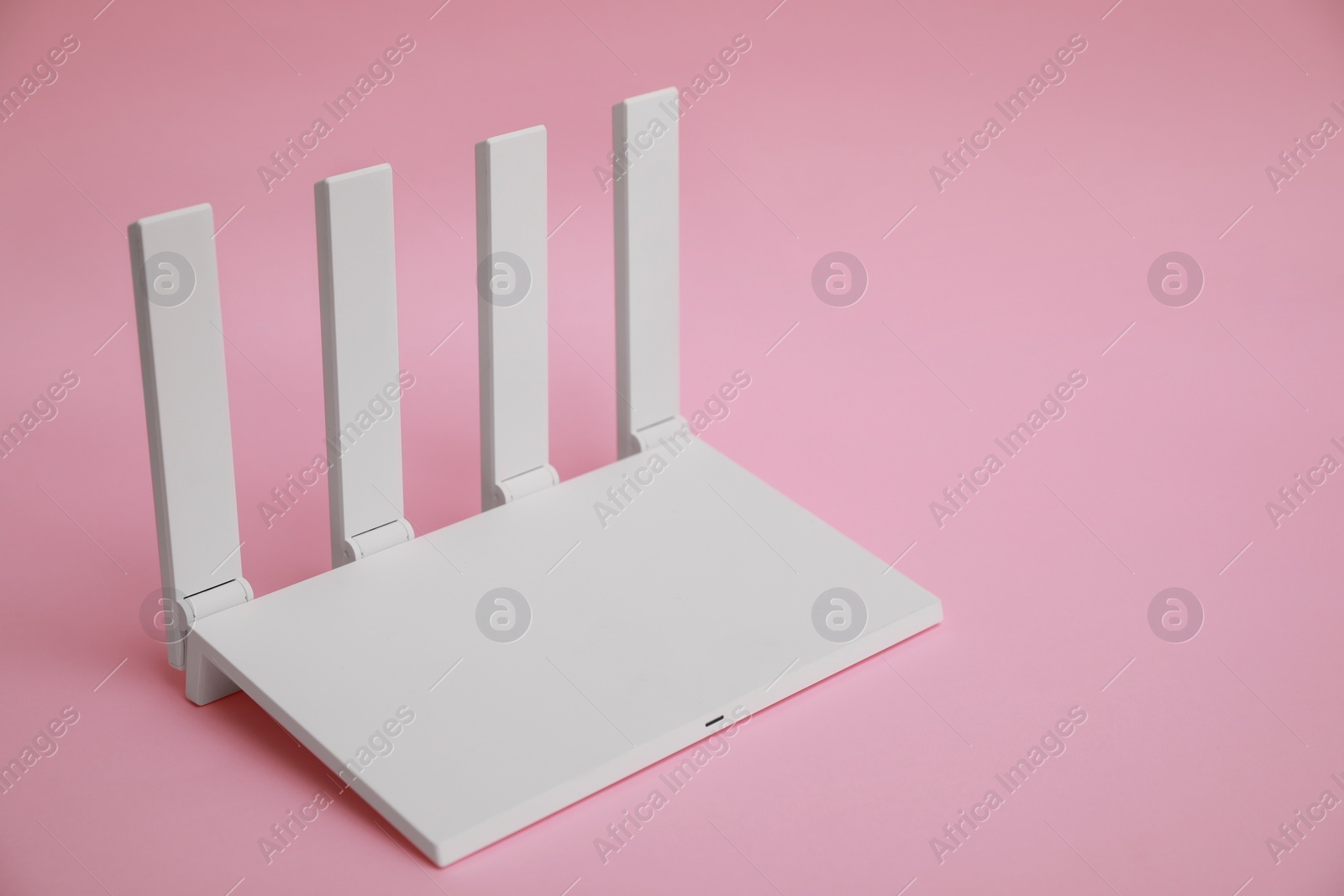 Photo of Modern Wi-Fi router on pink background. Space for text