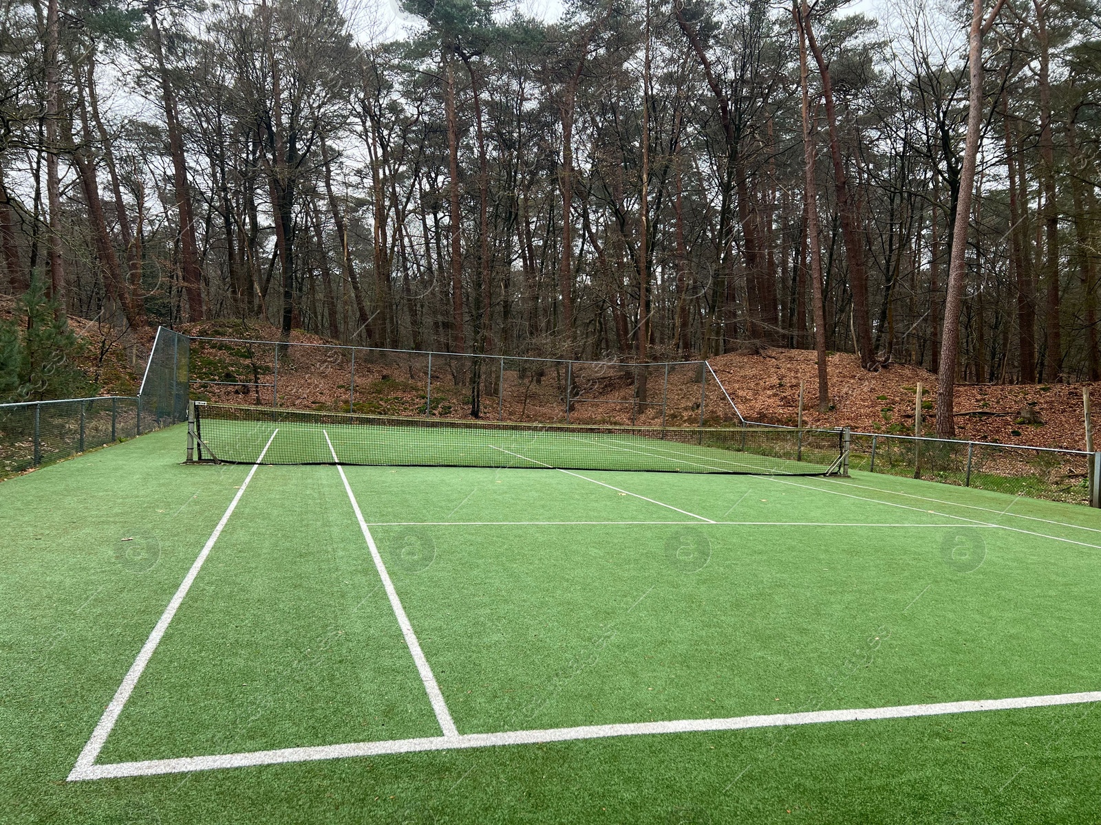 Photo of Tennis court with artificial grass and net outdoors