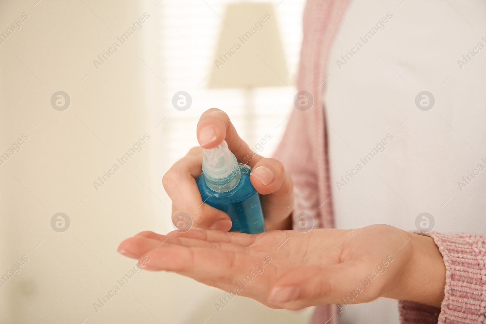 Photo of Woman applying antiseptic gel at home, closeup