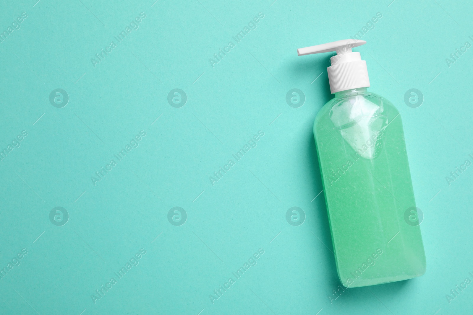 Photo of Bottle of face cleansing product on turquoise background, top view. Space for text