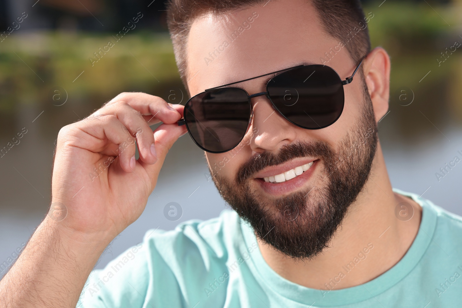 Photo of Handsome smiling man in sunglasses outdoors on sunny day