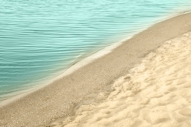 View of sea water and beach sand on sunny summer day