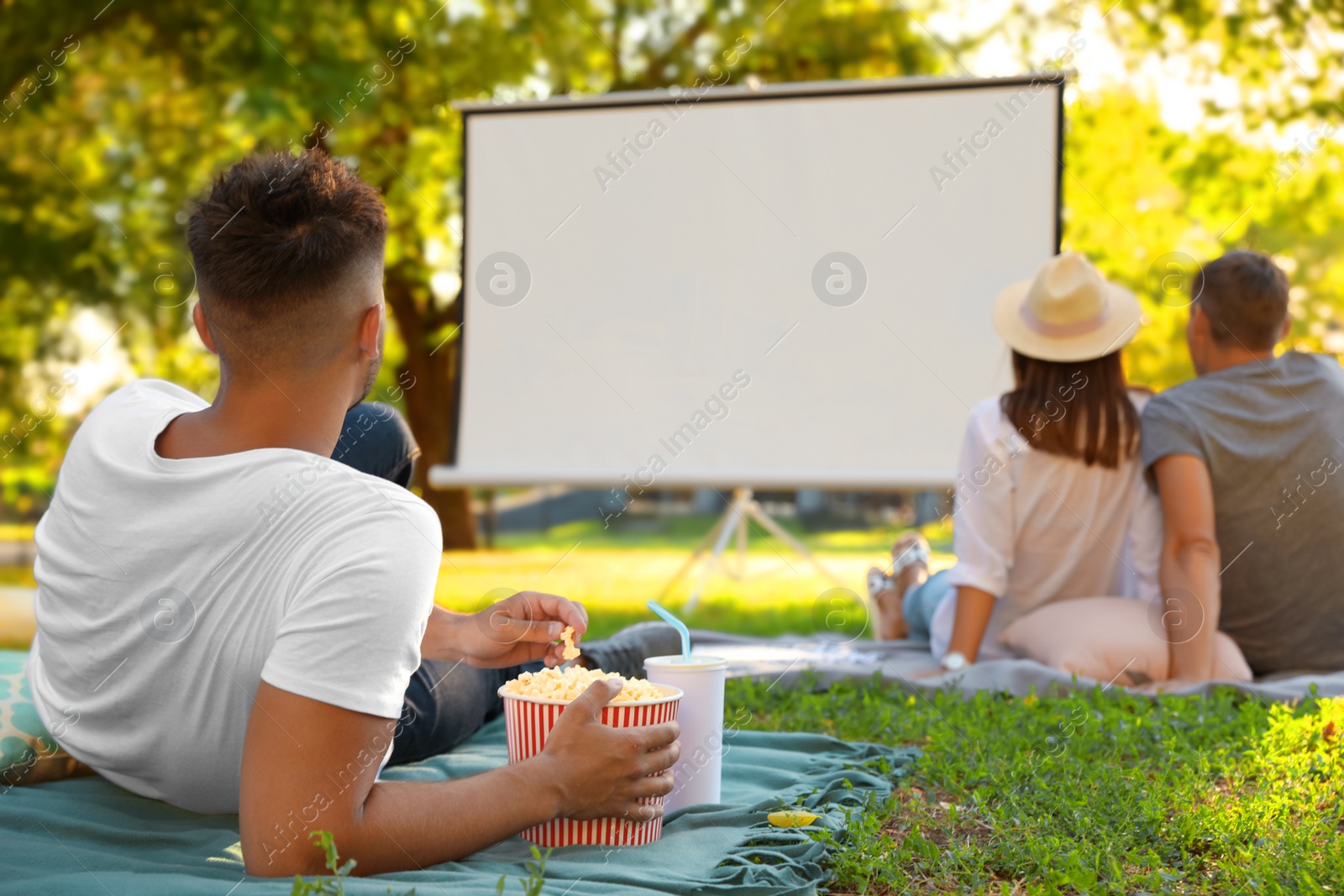 Photo of Young man with popcorn watching movie in open air cinema. Space for text