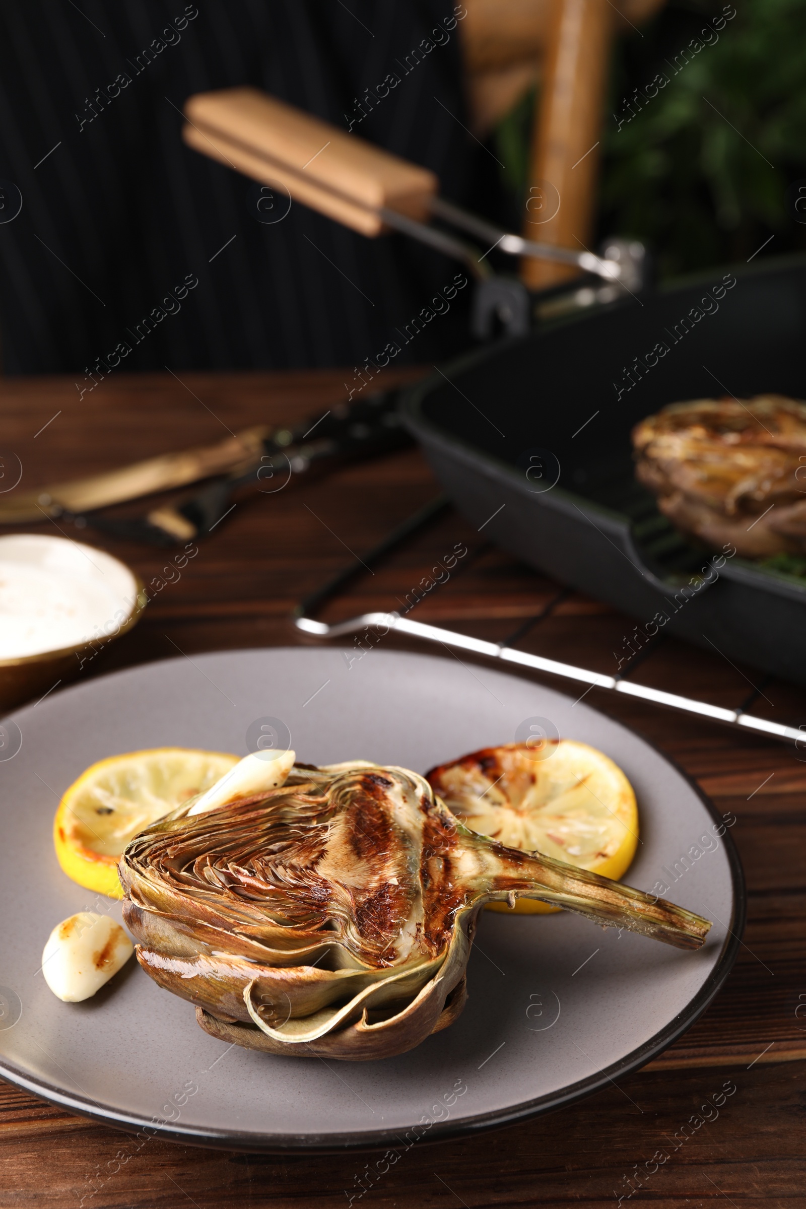 Photo of Tasty grilled artichoke served on wooden table